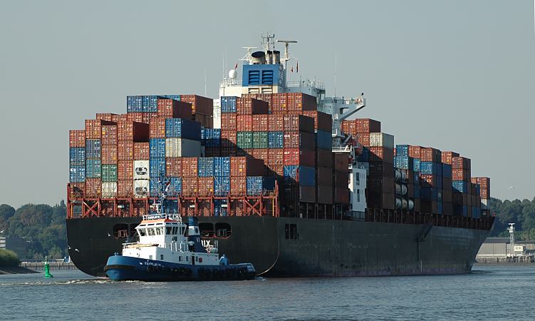 011_26036  Schlepper bringen einen Containerriesen aus dem Hamburger Hafen in die Fahrtrinne der Elbe; das Containerschiff ist hoch mit den grossen Metallboxen beladen.   www.christoph-bellin.de
