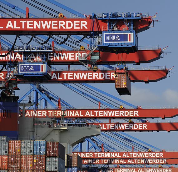 Fotos vom Containerhafen Hamburg - Containerbrcken Altenwerder  011_26094 Ein Container wird von der Containerbrcke von Bord des Schiffs gebracht. Das Container Terminal Altenwerder wird zu 74,9% von der Hamburger Hafen und Logistik AG HHLA und zu 25,1% von der Hapag-Lloyd AG betrieben.  An der Hauptkatze, die den Container transportiert, ist der ist auf blauem Grund der Schriftzug HHLA angebracht, auf den Auslegern der roten Containerbrcken steht "Container Terminal Altenwerder". www.hamburg-fotograf.com