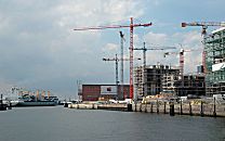 017_18971 Blick ber den Grasbrookhafen Richtung ELbe - ein Containerfrachter verlsst gerade den Hamburger Hafen und fhrt zur Nordsee; in der Bildmitte der ehem. Kaispeicher A, die zuknftige Elbphilharmonie - rechts die Baustelle (2007) der Hafencity / Kaiserkai mit den hohen Baukrnen. 