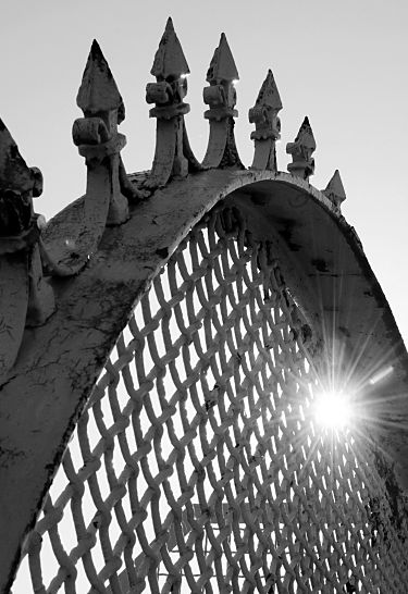 017_19008 Hamburg Fotografie: die Eisenspitzen des Metallzauns ragen in den Himmel - durch den Maschendraht strahlt die Sonne im Gegenlicht.  www.christoph-bellin.de