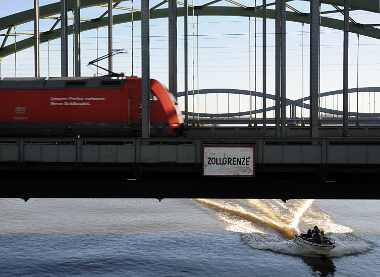 017_19018 ein roter Triebwagen auf den Elbbrcken beim Schild Zollgrenze . auf der Elbe fhrt ein Sportboot / Motorboot in voller Fahrt.   www.christoph-bellin.de