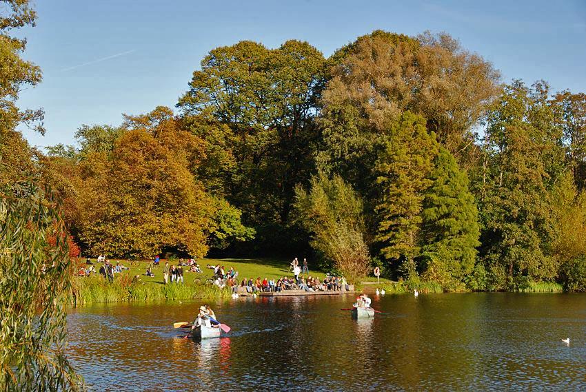 16_03813 der Hamburger Stadtpark hat sein prchtiges Herbstkleid angelegt; dicht gedrngt sitzen die Parkbesucher am Ufer des Stadtparksees in der warmen Herbstsonne; zwei Kanus fahren auf dem stillen See.   www.christoph-bellin.de