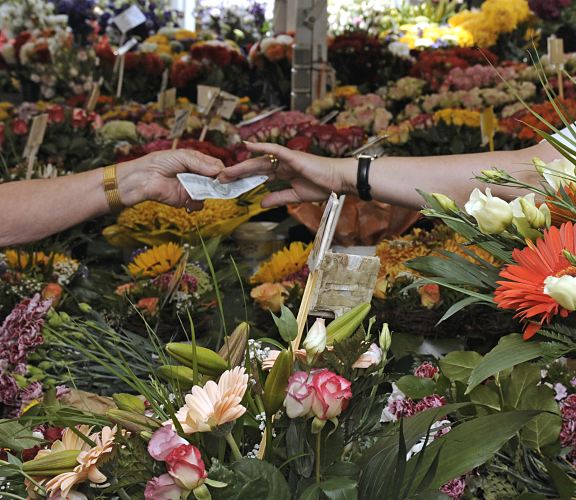 Blumenstand mit farbenprchtigen Schnittblumen auf dem Bergedorfer Wochenmarkt. Eine Kundin reicht gerade der Blumenverkuferin einen Geldschein. 