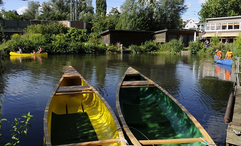 Kanus am Bergedorfer Fluss die Bille, eine Familie mit Kindern starte gerade zu einer Kanufahrt auf der Bille - zwei leere Boote liegen am Bootssteg. Die Bille kann mit dem Kanu flussaufwrts bis Reinbek befahren werden. 