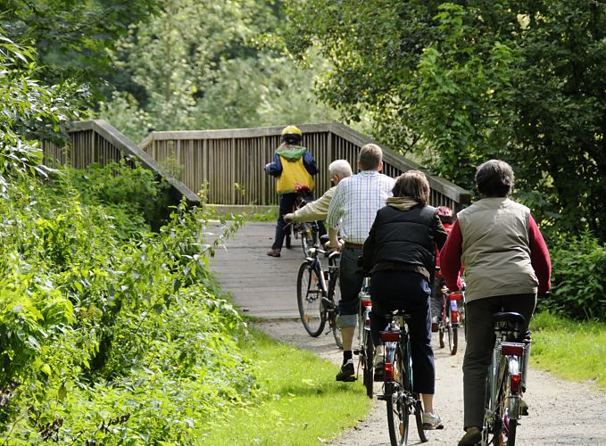 Bild vom Billewanderweg in Hamburg Bergedorf - Fahrradtour am Billeufer  Eine Familie macht auf dem Billewanderweg eine Fahrradtour. Eine Holzbrcke fhrt die Fahrradfahrer und Fahrradfahrerinnen ber den Hamburger Fluss.