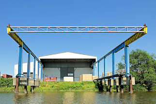 5698 Krananlage ber dem Wasser des Moorfleeter Kanals im Hamburger Stadtteil Billbrook - Lagerhalle am Ufer des Kanals.