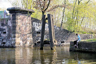6043 Altes Brckenfundament am Ufer des Tiefstackkanals in Hamburg Billbrook - ein Angler sitzt am Ufer.