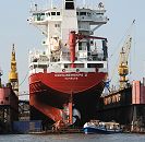 011_26-5959 Das Frachtschiff Containerships V ist im Hamburger Hafen eingedockt und bekommt eine neue Schiffschraube. Links und Rechts vom Trockendock zwei Werftkrane. Eine Barkasse der Hamburger Hafenrundfahrt zeigt den Hamburg Touristen die Arbeit im Hamburger Hafen. www.hamburg- fotograf.com