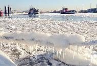 011_79_5688 Die Elbe ist mit Eisschollen dicht bedeckt - am Tau eines Schiffs, das am Ufer festgemacht hat, hängt eine dicke Schicht Eis mit Eiszapfen. Durch das Treibeis fahren zwei Hamburger Hafenfähren.
