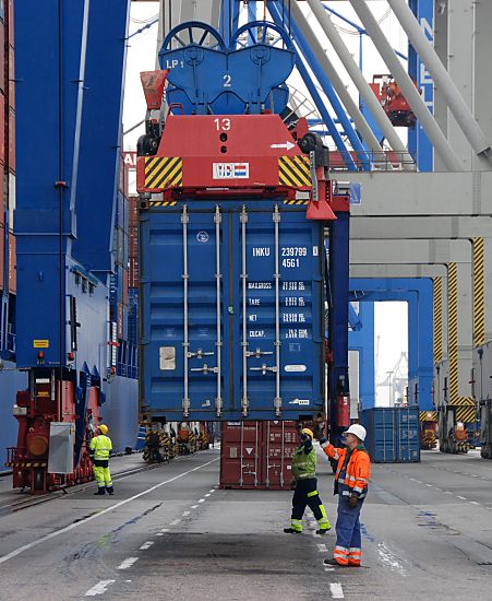 011_15719 Arbeiter in Sicherheitskleidung und mit Helm nehmen am Terminal Burchardkai einen Container in Empfang, der von der gerade Containerbrcke heruntergelassen wird.  www.fotograf-hamburg.de