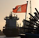 011_32795/00 die Hamburg Flagge weht im Wind am Heck eines Raddampfers der Hamburger Hafenrundfahrt. Im Hintergrund wird ein Frachter am Kai mit einem Kran gelöscht.   ©www.fotograf-hamburg.de