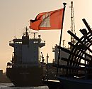 011_32795/00 die Hamburg Flagge weht im Wind am Heck eines Raddampfers der Hamburger Hafenrundfahrt. Im Hintergrund wird ein Frachter am Kai mit einem Kran gelscht.   www.fotograf-hamburg.de