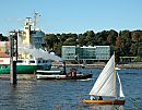 011_22976/00 ein Containerschiff fhrt auf der Elbe in Hhe Hamburg Neumhlen Richtung Nordsee; der historische Schlepper dampft Richtung Hafen - ein Segelboot segelt am Elbufer - an der anderen Elbseite die neue Architektur Hamburgs im ehem. Hafengebiet Altonas.  www.fotograf-hamburg.de