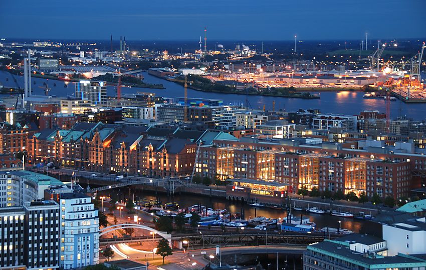 017_18927 Nachtaufnahme von der Speicherstadt und dem Hamburger Hafen. Die Hamburger Touristenattraktion wird in den Abendstunden knstlerisch beleuchtet / illuminiert, um die besondere Architektur zum Ausdruck zu bringen. Im Hintergrund Anlagen des Hamburger Hafens, in dem die ganze Nacht gearbeitet wird. 