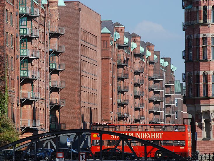 017_18940 ein roter Doppeldeckerbus der Hamburger Stadtrundfahrt berquert die Fleetbrcke Bei St. Annen; fr Hamburg -  Touristen gehrt die Speicherstadt sowie der Hamburger Hafen zu den Touristenattraktionen, dei gerne besucht werden. Die Dcher aus Kupfer unter den Giebeln der Speichergebude schtzen die dort angebrachten Winden, die die Ware an der Fleetseite des Gebudes transportieren.  www.christoph-bellin.de