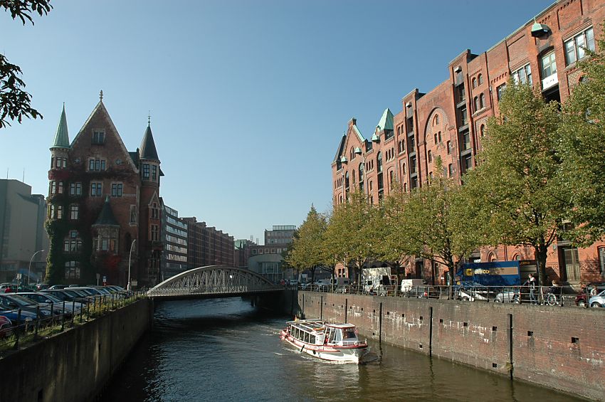 017_18945 eine Barkasse der Hafenrundfahrt durchquert mit den Hamburg - Touristen an Bord die Speicherstadt auf dem Brooksfleet; sie hat gerade die Neuerwegsbrcke passiert und ist wieder auf den Weg zur Elbe um dort auf der sightseeingtour den Hamburg Besuchern die Sehenswrdigkeiten des Hamburger Hafens zu zeigen; rechts die Strasse Hollndischer Brookfleet - Lastwagen werden mit Waren beladen.  www.christoph-bellin.de