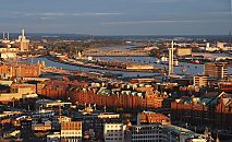 017_18926 Hamburg im Licht vom Sonnenuntergang - der rote Backstein der Speicherstadt leuchtet in der Abendsonne. In der linken Bildmitte verluft der Baakenhafen, an dessen vorderer Kaianlage die Bauarbeiten fr die Hamburger Architektur - Universitt / HafenCity Universitt Hamburg (HCU) begonnen haben. Im Hintergrund die Bgen der Elbbrcke ber die Norderelbe.