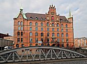 017_18939 Blick ber den genieteten Stahltrger der Neuerwegsbrcke zum Backsteingebude vom Sandtorquai-Hof, der 1888 errichtet wurde - rechts im Hintergrund Wohngebude auf der anderen Seite des Zollkanals "Bei den Neuen Mhren". Die Strasse im Vordergrund hat Kopfsteinpflaster.