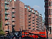 017_18940 ein roter Doppeldeckerbus der Hamburger Stadtrundfahrt berquert die Fleetbrcke Bei St. Annen; fr Hamburg -  Touristen gehrt die Speicherstadt sowie der Hamburger Hafen zu den Touristenattraktionen, die sie auf ihrer Sightseeing-Tour gerne besuchen. Die Dcher aus Kupfer unter den Giebeln der Speichergebude schtzen die dort angebrachten Winden, die die Ware an der Fleetseite des Gebudes transportieren.