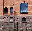017_18961 Fassade eines Speichergebäudes an der Fleetseite; es ist Ebbe - eine Leiter führt an der Hauswand zu einer Luke. Holzbalken die zum Schutz der Mauer vor anlegenden Schiffen angebracht wurden sind vom Zahn der Zeit zerfressen. 