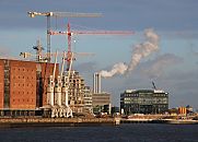 017_18969 Blick von der Elbe auf die Krne der Baustelle am Grasbrookhafen; im Vordergrund links der ehemalige Kaispeicher A und die Hafenkrne; das historische  Lagergebude wurde 1876 am Kaiserhft erbaut und im II. Weltkrieg zerstrt. Anfang der 1960 er Jahre wurde das jetzige Gebude errichtet, das der Architekt Werner Kallmorgen entworfen hat - es steht unter Denkmalschutz. In Zukunft soll das Speichergebude fr die geplante Elbphilharmonie, einem weiteren Wahrzeichen Hamburgs, genutzt werden - die Umbauarbeiten haben begonnen. 