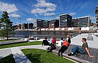 017_18973 die Marco-Polo-Terrassen in der Hafencity sind fertig gestellt - Besucher nutzen die Sitzgelegenheiten aus Holz um in der Mittagspause in der Sonne am Hamburger Hafen zu sitzen. Im Hintergrund die Silhouette der neugebauten Huser am Kai des ehemaligen Grasbrookhafens.