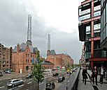 017_18980 Blick in die Strasse Am Sandtorkai in der Hamburger Speicherstadt - rechts die neue Bebauung der Hafencity, die mit der Rckseite am Sandtorhafen steht. In der Bildmitte das ehemalige Kesselhaus, das die Speicherstadt mit Energie versorgte; das historische Gebude steht jetzt unter Denkmalschutz - die Schornsteine wurden durch ein Metallgerst ersetzt. Das Gebude wird als Informationscenter genutzt - ein grosses Modell der zuknftigen Hafencity ist dort aufgebaut.  www.christoph-bellin.de