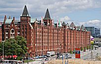 017_18984 die Fassade der Lagerhuser mit ihren Trmen und Giebel am Brooktorkai in der Sonne.  Im Vordergrund ist Sand aufgeschttet, die Bauarbeiten an der Hafencity gehen weiter - auf der rechten Bildseite ein Ausschnitt der Deichtorhallen.  www.christoph-bellin.de