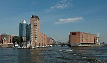 017_18995 Blick in den Sandtorhafen, die Sandtorhafenklappbrcke ist geschlossen; links die neue Architektur der Brohuser vom Hanseatic Trade Center HTC, ganz links das historische Gebude der Speicherstadt - Polizeiwache. Rechts der Kaispeicher A. Im Vordergrund fhrt ein kleines Motorboot auf die Elbe.  www.christoph-bellin.de