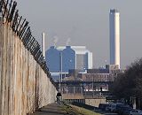 017_19014 hoher Zollzaun auf der Veddel - ein Fahrradfahrer fhrt auf dem Deich. Hinter der S-Bahnstation Veddel liegt das Kraftwerk Tiefstack mit seinen hohen Schornsteinen. Auf der anderen Seite des Zaun befindet sich der Hamburger Spreehafen, in dem Hausboote vor Anker liegen. Fotograf Christoph U. Bellin   www.christoph-bellin.de