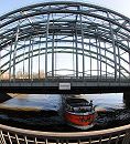 017_19016 im Vordergrund das Gelnder der Freihafenelbbrcke, dahinter die Eisenbahnbrcke, zwischen deren Streben der Bogen der Autobahnbrcke ber die Elbe bei Rothenburgsort zu erkennen ist. Ein rotes Binnenschiff passiert gerade die Zollgrenze auf der Elbe und fhrt in das Hamburger Freihafengebiet in. Hamburgsbilder :: www.christoph-bellin.de