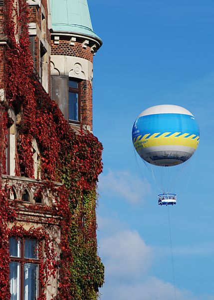 017_18960 Ban der Fassade vom Lagerhaus in der Hamburger Speicherstadt rankt der Wein; das Laub der Kletterpflanze ist im Herbst rt gefrbt. Im Hintergrund ein Heissluftballon, der mit einem Seil am Boden gehalten wird und den Hamburgern und Hamburg Touristen einen Ausblick auf die Stadt gibt.   www.christoph-bellin.de