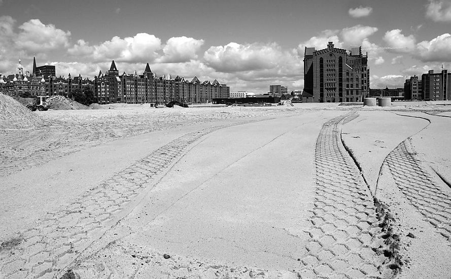 017_18962 Panorama der Hamburger Speicherstadt - in der rechten Bildmitte der Kaispeicher B, links die Speicherhuser am Brooktorkai und bei St. Annen; Reifenspuren im Sand; um die entstehende Hafencity nach heutigen Massstben gegen Hochwasser zu sichern muss das Gelnde mindestens 7,5m NN liegen. Mengen an Sand werden mit Lastwagen herangebracht, um das Gebiet zu aufzuschtten.  www.christoph-bellin.de