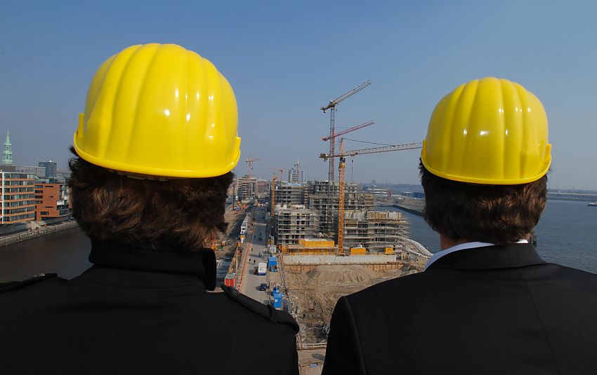 017_18967 dBlick vom Kaispeicher A, der zuknftigen Elbphilharmonie am Hamburger Hafen auf die Hafencity Baustellen Januar 2007; die Bauarbeiten am Kaiserkai sind fortgeschritten, Baukrne ragen in den blauen Hamburger Himmel. Zwei Besucher mit Bauhelm blicken interessiert auf das Areal der zuknftigen Hafencity zwischen Sandtorhafen und Grasbrookhafen. www.christoph-bellin.de