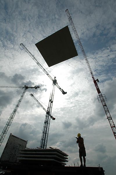 017_18970 Baustelle in der Hafencity am Dalmannkai; Baukrne ragen in den Himmel, ein Baurarbeiter dirigiert einen Baukran, der eine grosse Betronplatte trt mit Sprechfunk zu dem Bestimmungsort. www.christoph-bellin.de