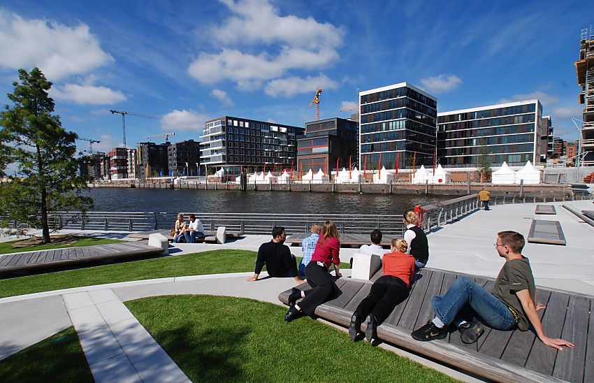 017_18973 die Marco-Polo-Terrassen in der Hafencity sind fertig gestellt - Besucher nutzen die Sitzgelegenheiten aus Holz um in der Mittagspause in der Sonne am Hamburger Hafen zu sitzen. Im Hintergrund die Silhouette der neugebauten Huser am Kai des ehemaligen Grasbrookhafens. www.christoph-bellin.de