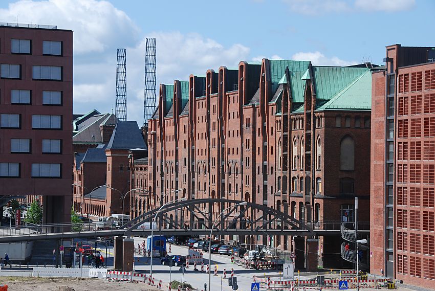 017_18979 die Bebauung der Strasse "Am Sandtorkai" in der Hamburger Speicherstadt ist geprgt durch die historischen Backsteinspeicher und die moderne Architektur der Hafencity. Im Vordergrund die Kibbelstegbrcke, dahinter symbolisieren das runde hohe Eisengerst die ehemaligen Schornsteine vom Kesselhaus.  www.christoph-bellin.de