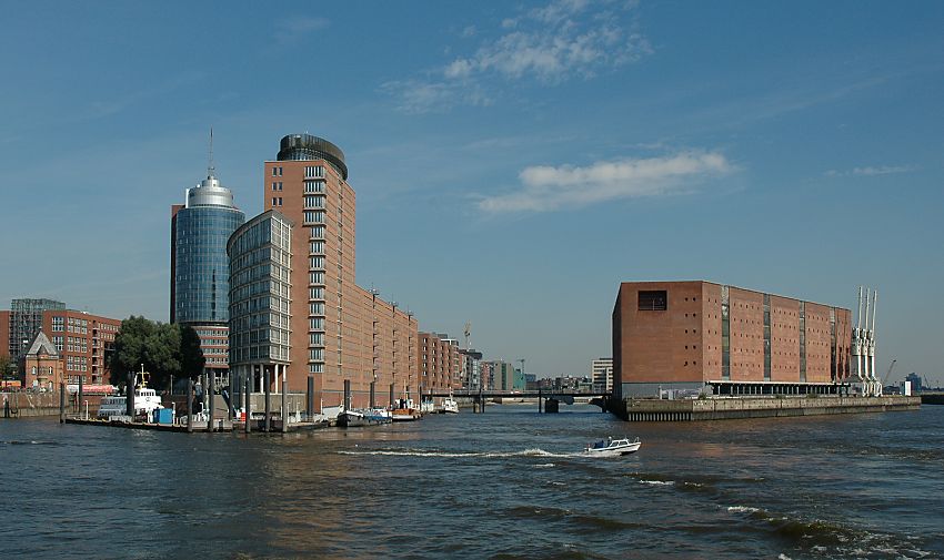 017_18995 Blick in den Sandtorhafen, die Sandtorhafenklappbrcke ist geschlossen; links die neue Architektur der Brohuser vom Hanseatic Trade Center HTC, ganz links das historische Gebude der Speicherstadt - Polizeiwache. Rechts der Kaispeicher A. Im Vordergrund fhrt ein kleines Motorboot auf die Elbe.  www.christoph-bellin.de