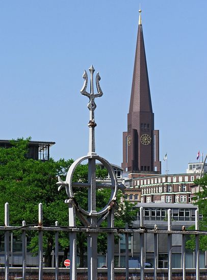 017_19003 Eisenzaun, der die ehem. Zollgrenze am Hamburger Freihafen bildet; ein Dreizack ist als Dekorelement an der Zaunspitze angebracht. Im Hintergrund der Kirchturm der Hamburger Hauptkirche St. Jakobi. www.christoph-bellin.de