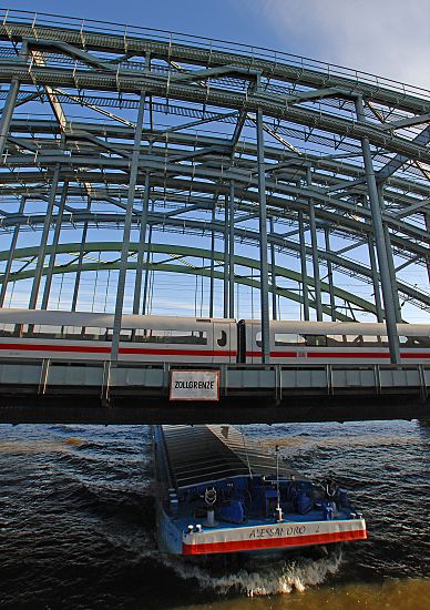 017_19015 Zollgrenze an den Hamburger Elbbrcken. Ein Binnenschiff fhrt in voller Fahrt Richtung Hamburgs Hafen - auf der Brcke fhrt ein Personenzug.  www.christoph-bellin.de