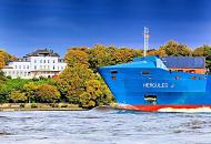 1033_0692  Das Feederschiff HERCULES J luft aus dem Hamburger Hafen aus und fhrt elbabwrts; im Hintergrund der bewaldete Elbhang mit herbstlich gefrbten Laubbumen. Eine weisse Villa steht mit Blick auf die Elbe steht zwischen den Bumen.