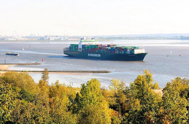 1042_9612 Blick vom Elbberg beim Falkensteiner Ufer ber den Herbstwald auf die Elbe. Ein Containerfrachter verlsst hochbeladen Hamburg. Im Hintergrund das Mhlenberger Loch und Gebude der Airbuswerke auf Hamburg Finkenwerder. 