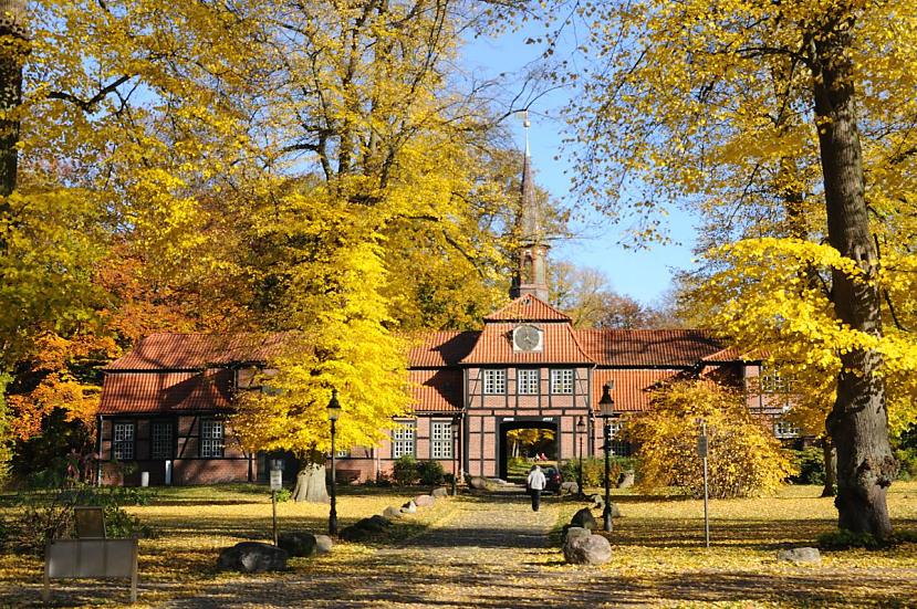 1611_1730 Die Herbstsonne scheint auf die Herbstbume, die beim historischen Torhaus von Hamburg Wellingsbtel stehen. Der Rasen vor dem historischen Gebude ist mit gelben Blttern bedeckt; ein Passant geht auf dem Kopfsteinpflaster zum Fachwerkgebude des 1757 errichteten Torhauses. Herbstbume am Torhaus von Hamburg Wellingsbttel - Fotos aus den Hamburer Stadtteilen.