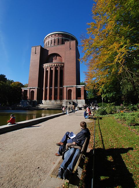 16_0379 Herbst im Winterhuder Stadtpark - das Laub der Bume am Hamburger Planetarium sind herbstlich gefrbt. Besucher des Parks sitzen oder liegen in der Herbstsonne unter blauem Himmel auf Bnken oder am Rand des Wasserbassins vor dem historischen Backsteingebude.    www.christoph-bellin.de