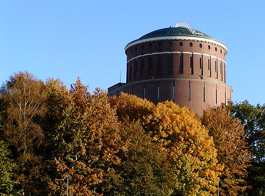 16_03797 Blick ber die Hamburger Jahn-Kampfbahn zum Turmgebude des Winterhuder Planetariums - die Kuppel des ehemaligen Wasserturms ragt aus den Herbst-Bumen heraus. In der Sonne strahlen die gelben und rtlichen Bltter vom Herbst-Laub.    www.christoph-bellin.de