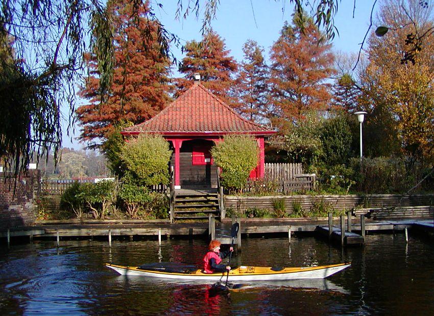 16_03808 der Bootsverleih auf der Liebesinsel im Hamburger Stadtpark hat im Sptherbst geschlossen, der Bootssteg ist leer - die Tretboote und Kanus sind in das Winterlager gebracht; auch der rote chinesisch anmutende Kiosk auf der Stadtpark-Insel hat nicht mehr geffnet. Die Sumpfzypressen am Seeufer tragen ihre rote Herbstfrbung - im Vordergrund fhrt ein Kajak Richtung Ausfahrt zum Goldbekkanal.   www.christoph-bellin.de