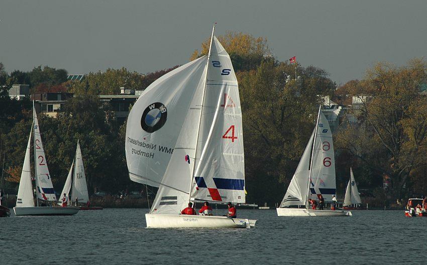 16_03825 vor der Kulisse der herbstlichen Bume am Alsterufer fhrt ein Segelschiff auf der Hamburger Aussenalster mit Spinnaker in voller Fahrt vor dem Wind - im Hintergrund weitere Segelboote, die an der wohl letzten Regatta der Hamburger Segelsaison auf der Alster teilnehmen.   www.christoph-bellin.de