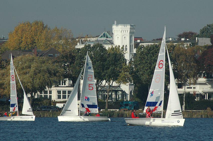 16_03826 die weisse historische Architektur an der Strasse "Alsterufer" ragt hinter den Herbstbumen heraus - im Vordergrund kreuzen Segelboote auf der Aussenalster.  www.christoph-bellin.de