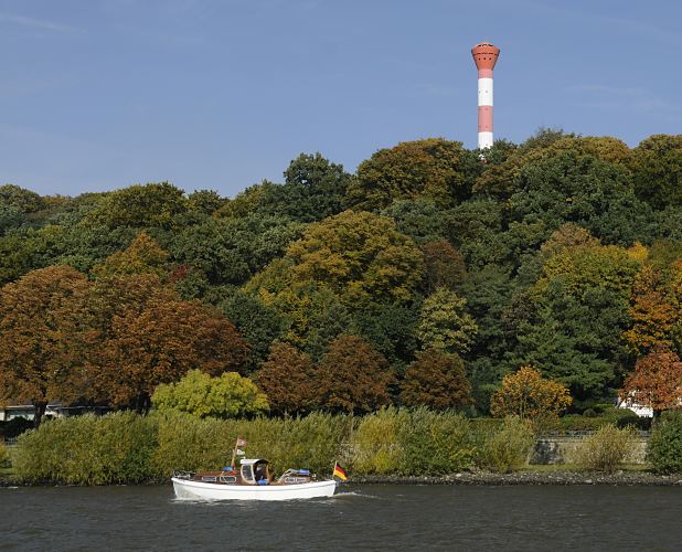 Fotografien von Hamburg | Aufnahmen der Jahreszeiten in Hamburg / Hamburg im Herbst  16_038163 Der Leuchtturm / Leuchtfeuer Wittenberge ragt aus den herbstlich gefrbten Bumen des Waldes am Elbhang empor. Ein weisses Motorboot fhrt nahe des Elbufers in der Herbstsonne. Bald ist die Sportboot-Saison beendet und das Schiff wird ber Winter in das sichere Winterlager gebracht.  www.christoph-bellin.de