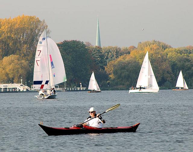 267_0367 Segelboote und Kanufahrer auf der Aussenalster in der Herbstsonne - die Bume am Alsterufer strahlen in herbstlichen Farben. Zwischen den Baumwipfeln der Kirchturm der St. Nikolaikirche am Klosterstern.